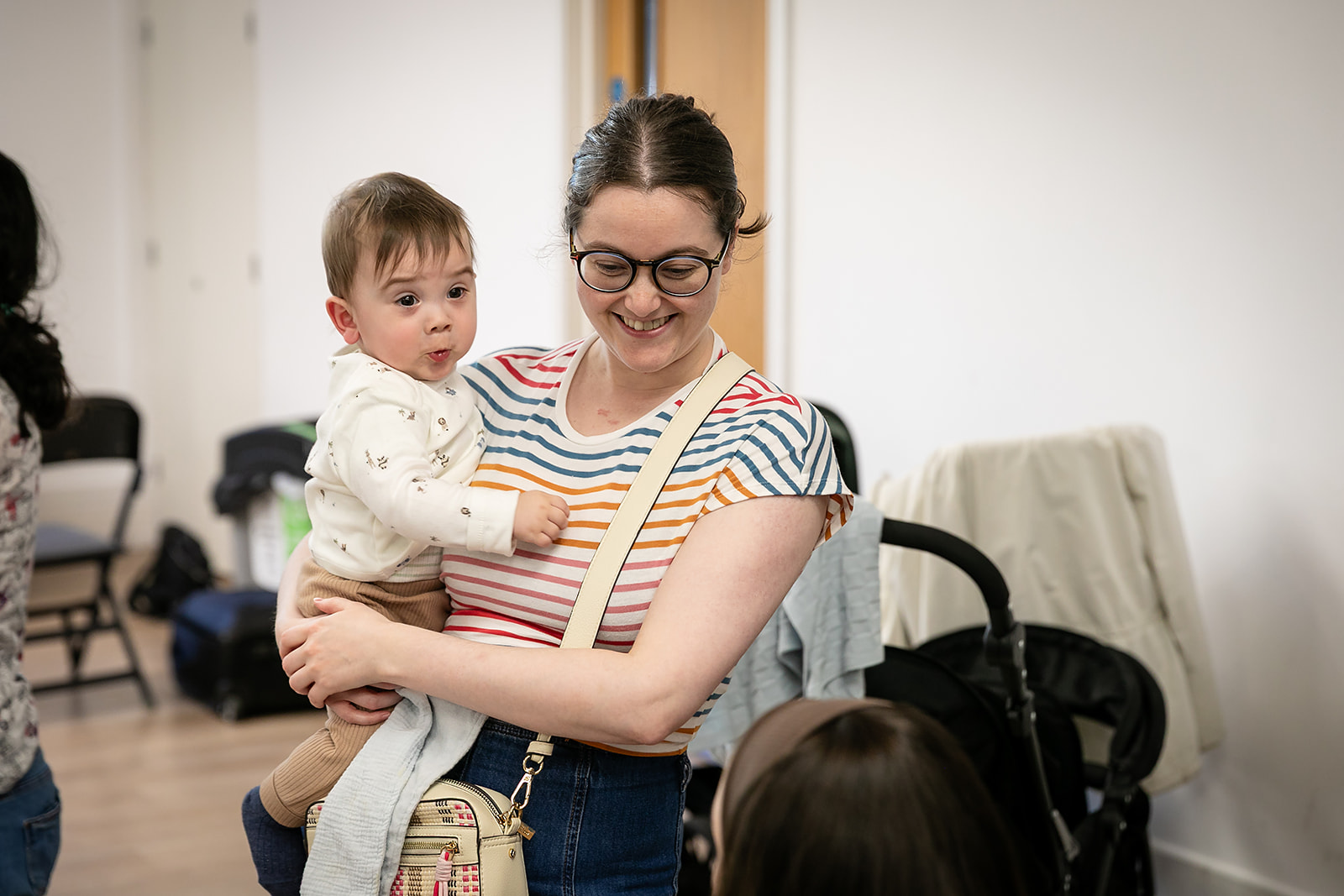 Mother with Baby Parent holding a baby while attending a Mother to Mother support group, connecting with other families in a welcoming community.